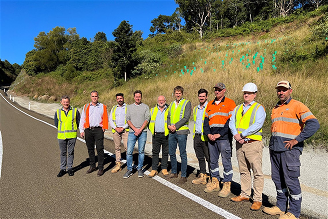 Staff, Mayor and Councillors in hi-vis standing at side of newly sealed and marked road